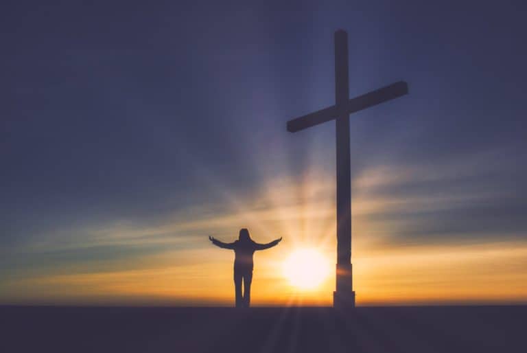 Homme devant le soleil levant avec une croix